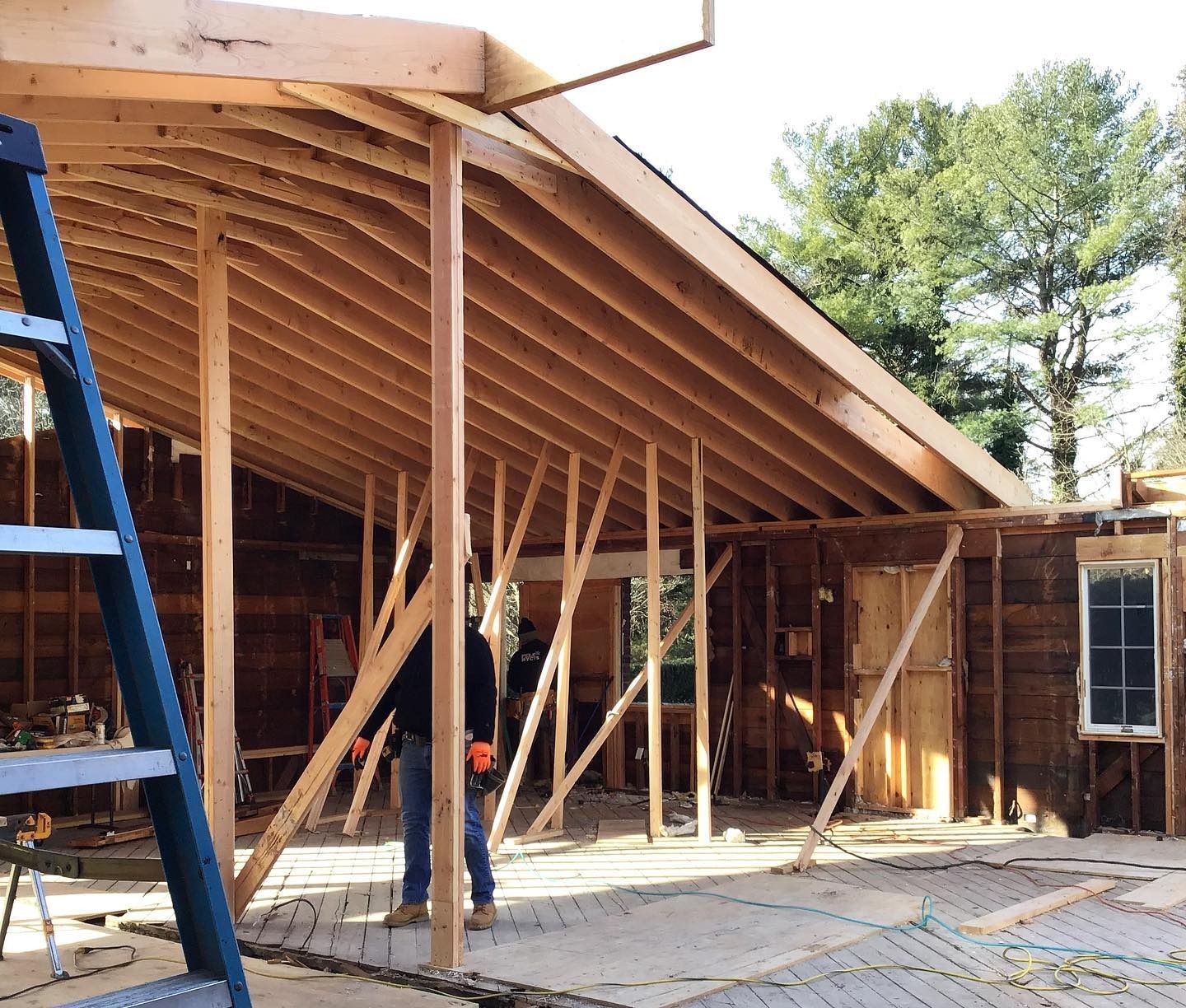 Construction site: wooden frame of a building addition, with workers inside and a ladder.