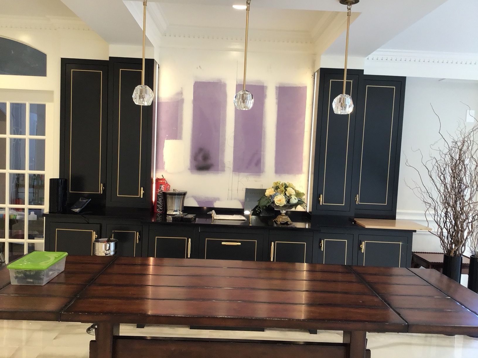 Kitchen with dark cabinets, a wooden table, and hanging globe lights.