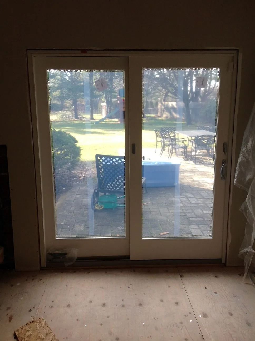 Sliding glass doors open to a patio with outdoor furniture. Interior is unfinished.