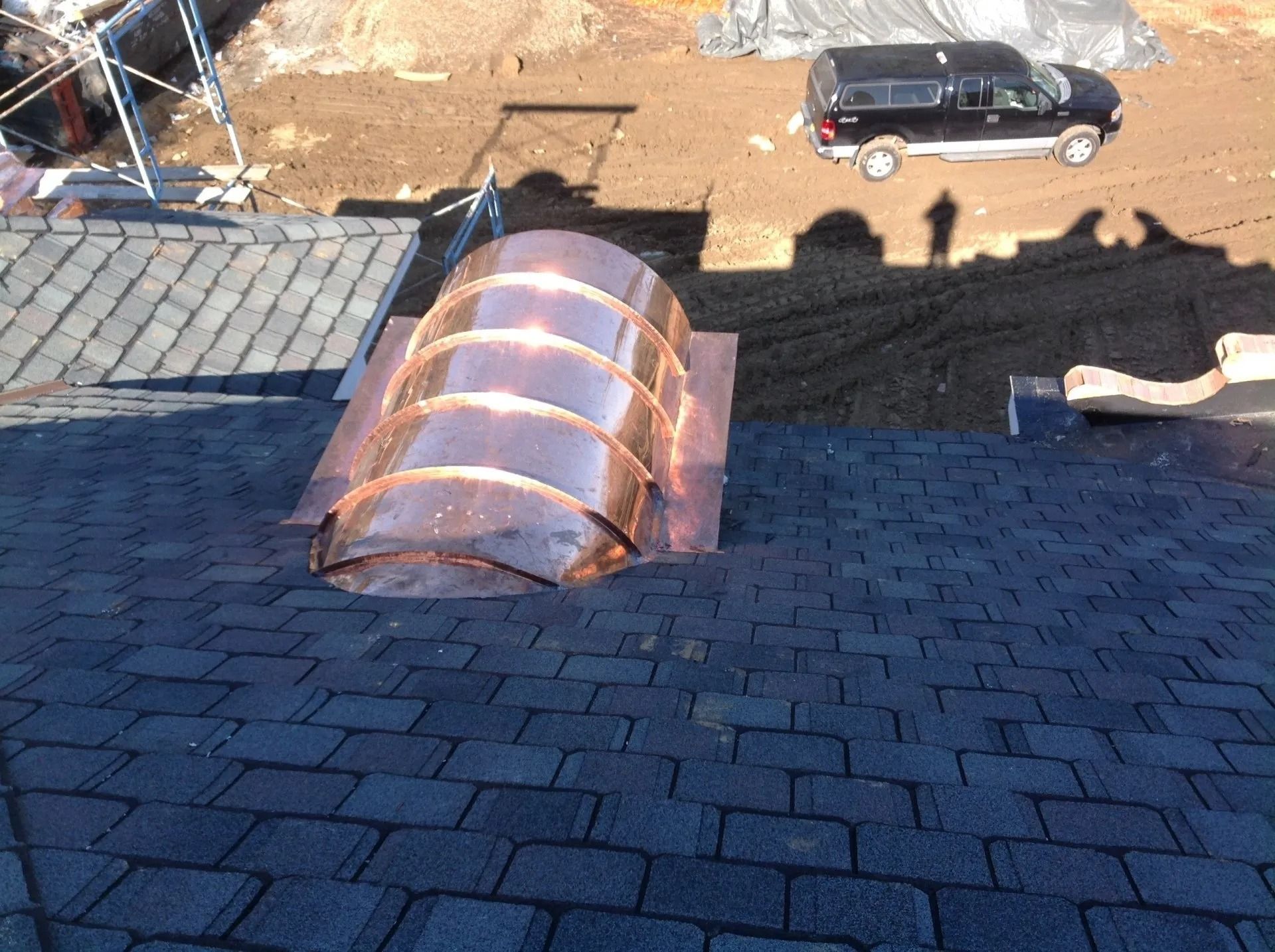 Copper-covered skylight on a dark asphalt shingle roof; a black SUV and shadows are visible in the background.