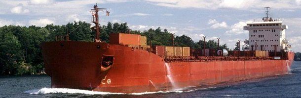 A large red ship is floating on top of a body of water.