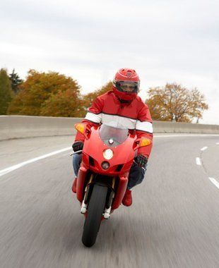 A man is riding a red motorcycle on a highway