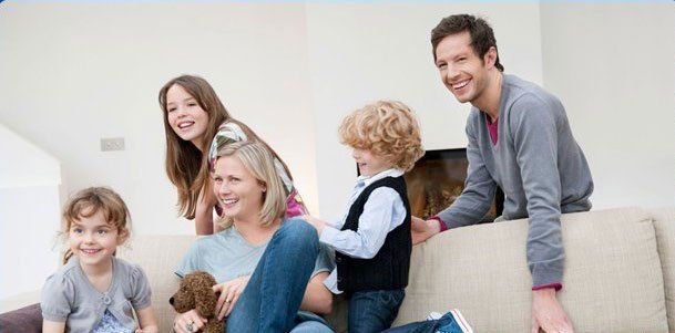 A family is sitting on a couch with a dog.