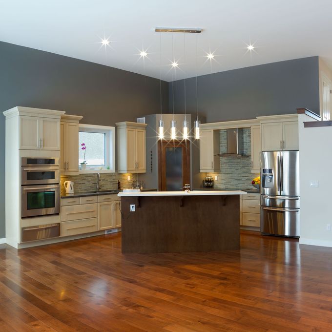 Modern kitchen with dark wood floors, stainless steel appliances, white cabinets, and a large island