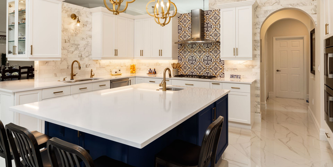 Elegant white kitchen with marble island, gold accents, and black bar stools