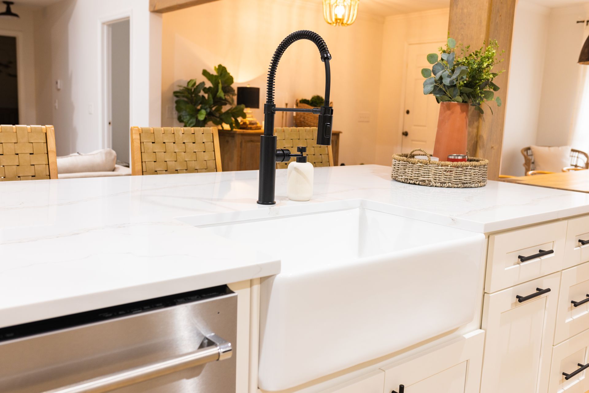 Modern kitchen with white countertops, black faucet, farmhouse sink, and woven basket decor[final]