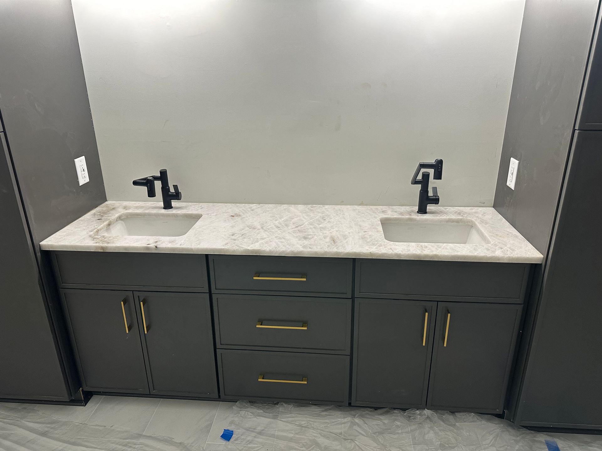 Double sink vanity with dark cabinets and light countertop in a restroom.