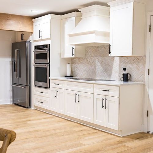 Bright modern kitchen with white cabinets, stainless steel appliances, and light wood floors