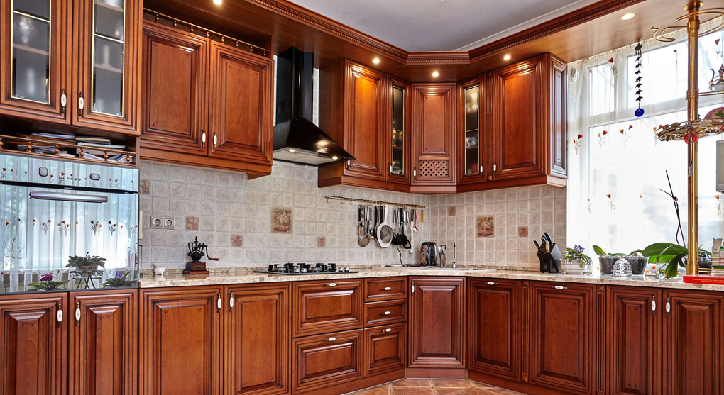 Bright kitchen with wooden cabinets, tiled backsplash, and sunlight through a window