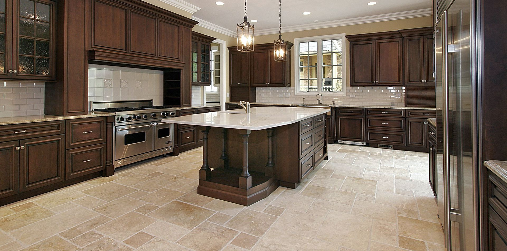 Bright kitchen with wood cabinets, granite counters, stainless steel fridge, and a central island.