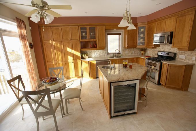 Sunlit kitchen with wood cabinets, island, and a small dining table by the window