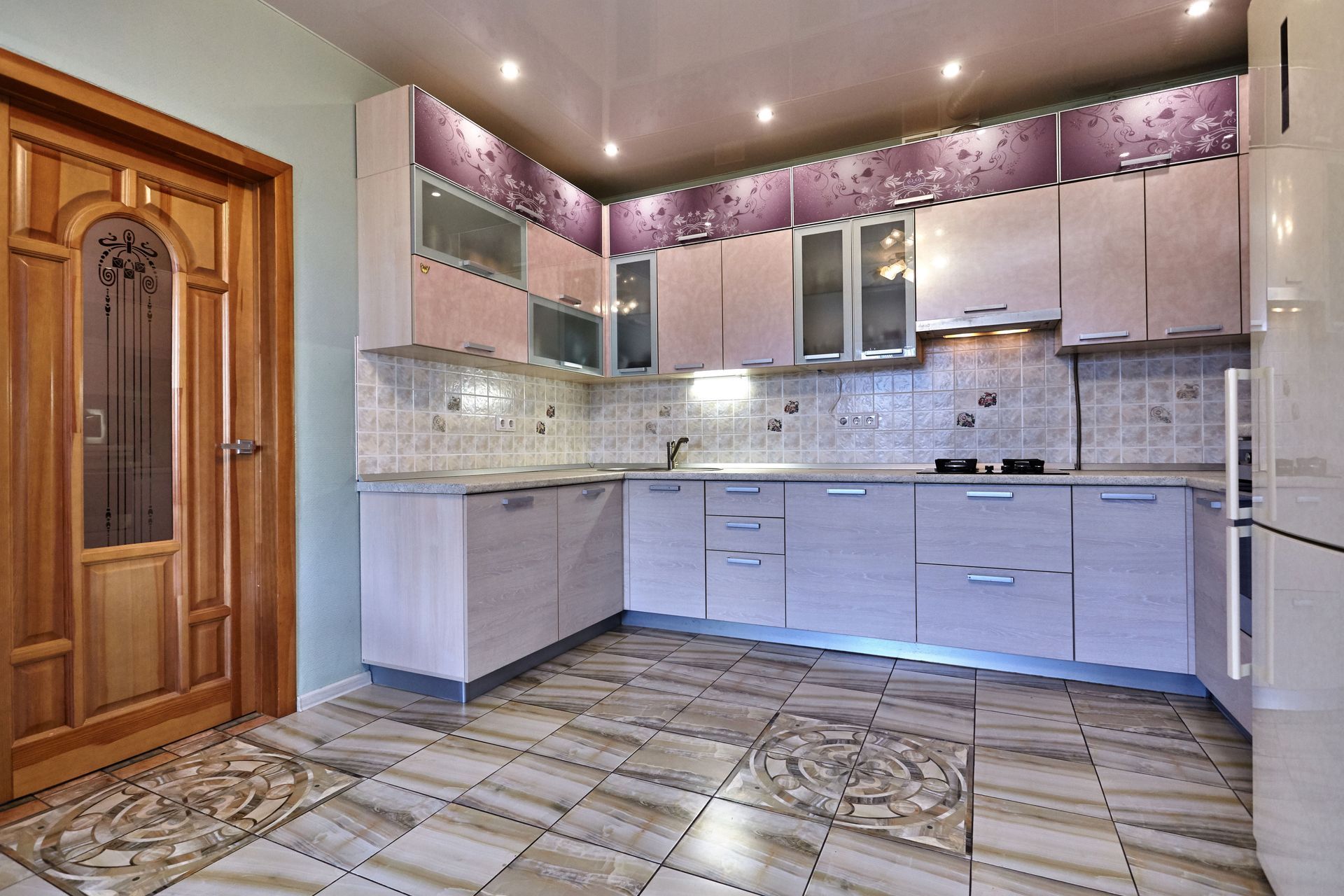 Modern kitchen with white cabinets, stainless appliances, pink mosaic backsplash, and tiled floor