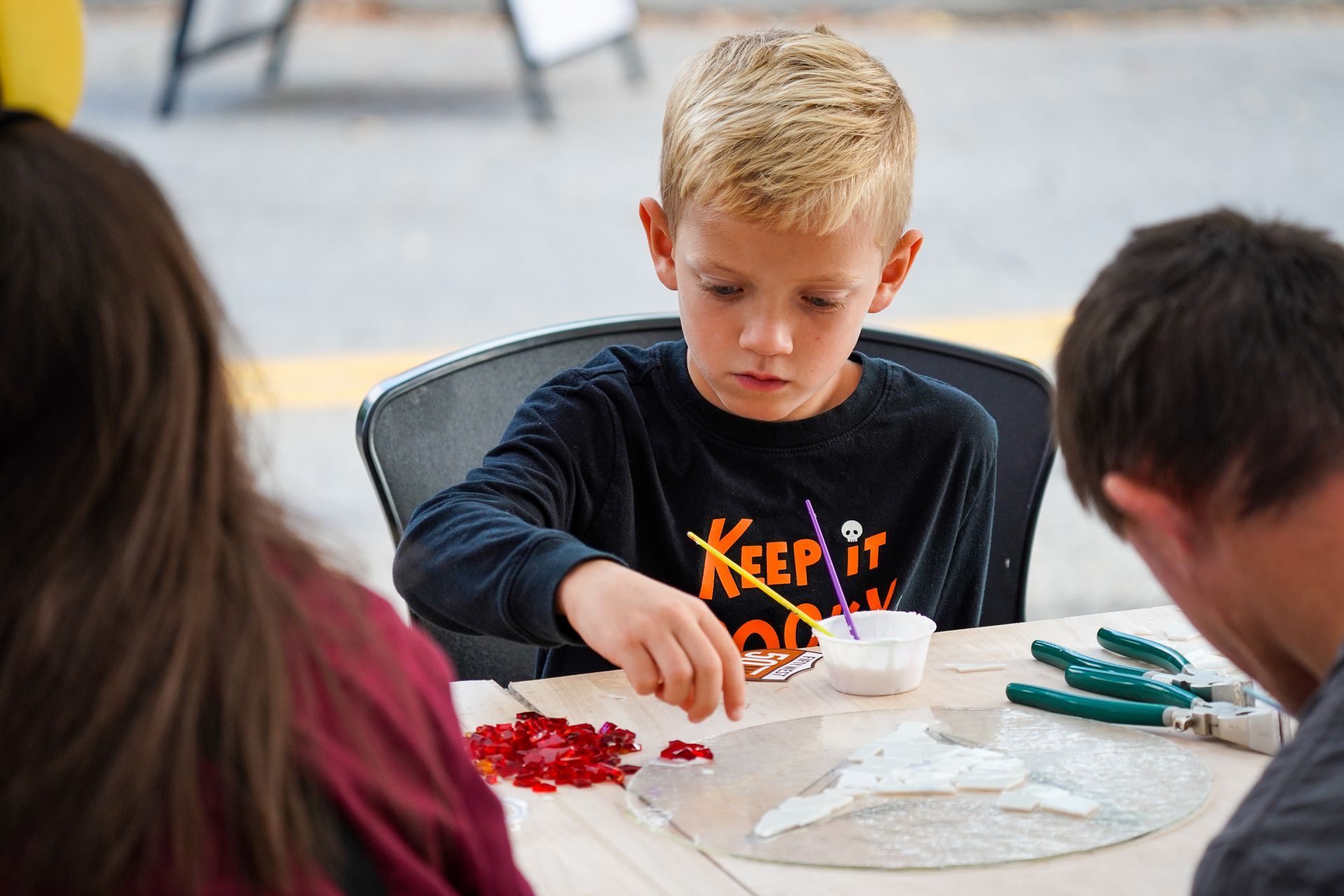 a young boy is sitting at a table making a craft