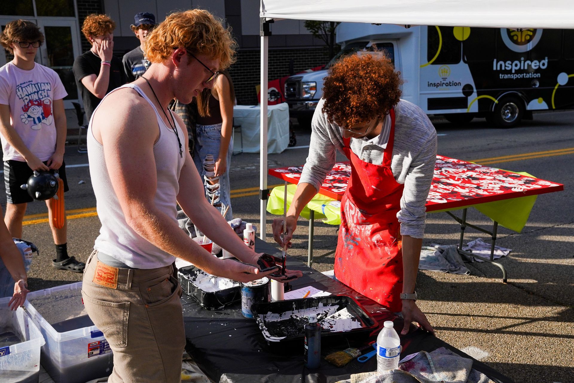 a group of people standing around a table with a truck in the background that says inspire