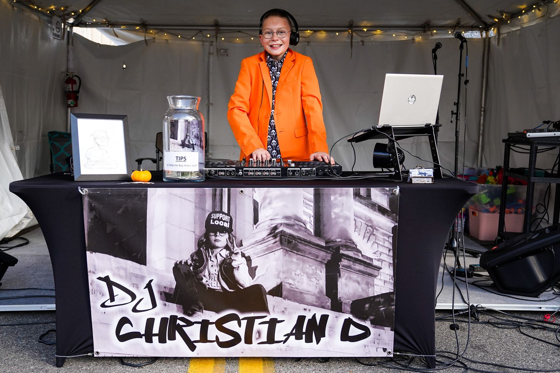 a man in an orange jacket is standing behind a dj booth