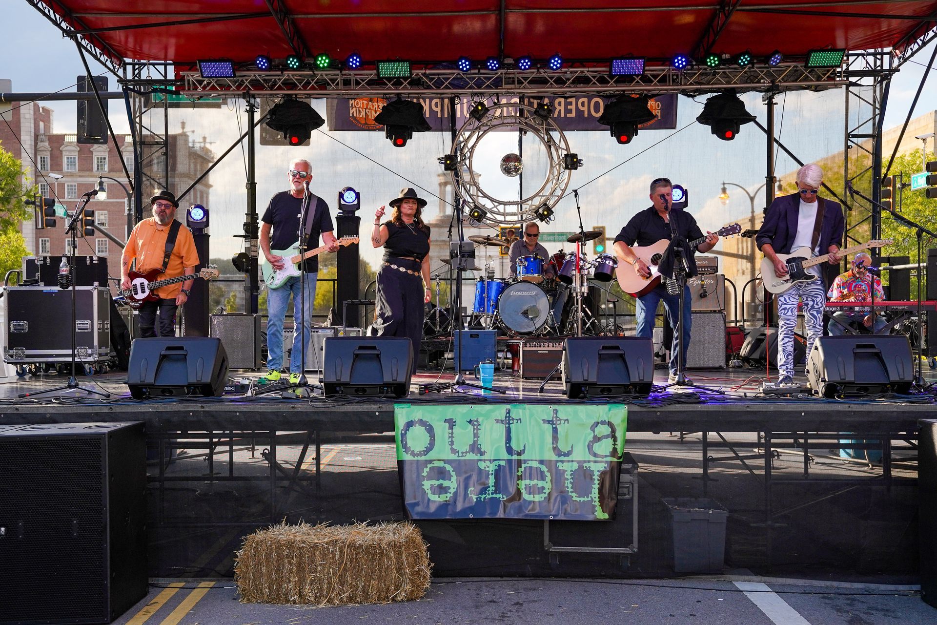 a band is playing on a stage with a sign that says outta here