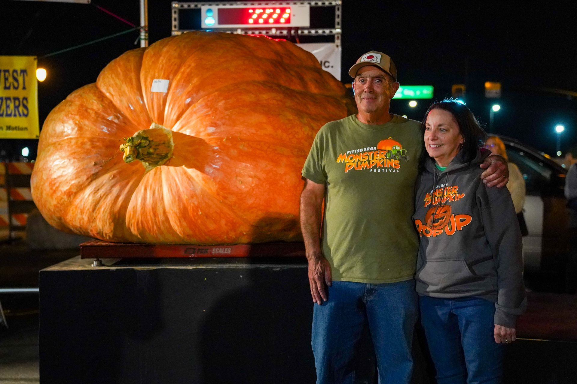 2 people in front of a large pumpkin