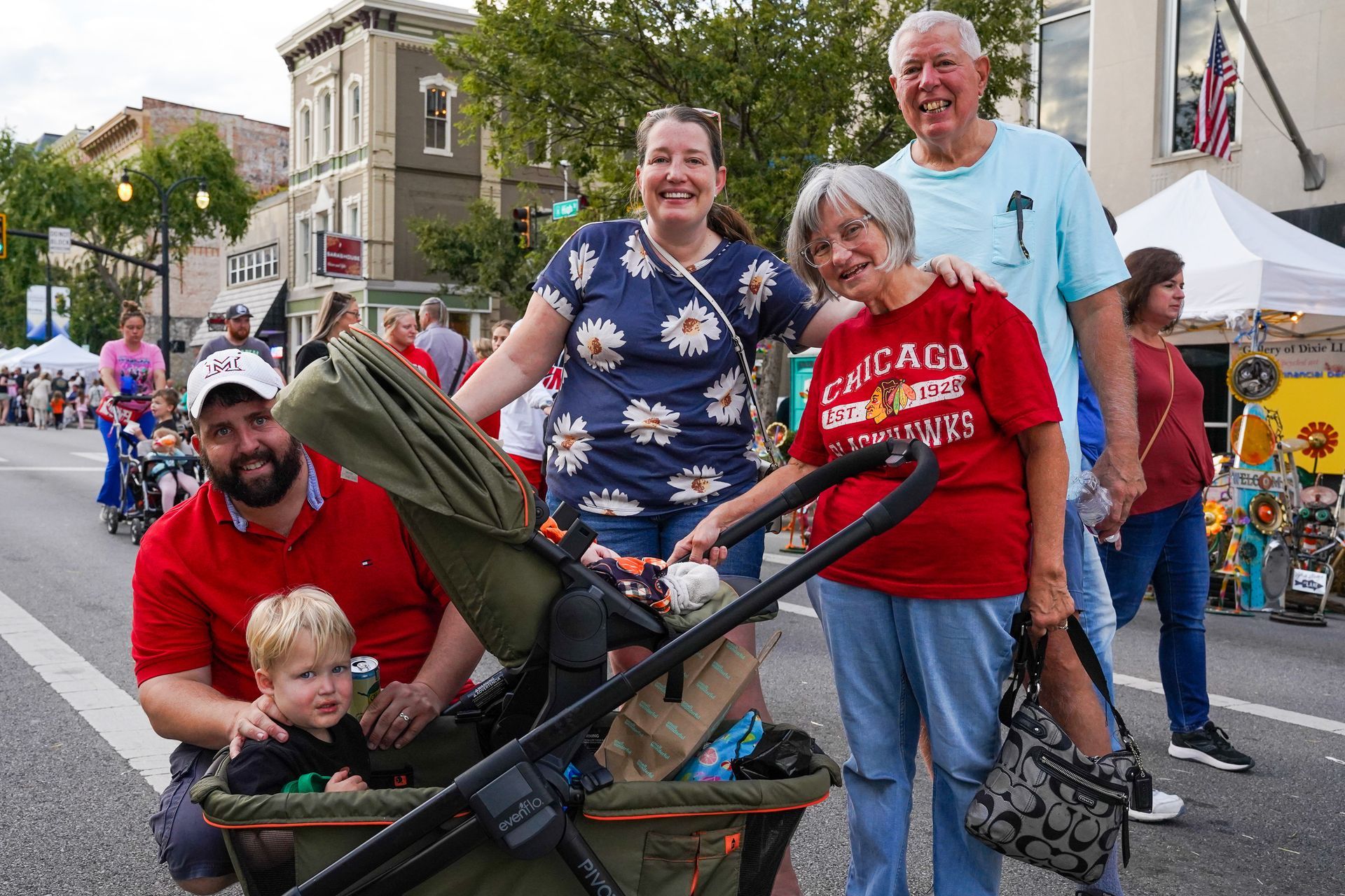 a group of people are standing on a street with a stroller