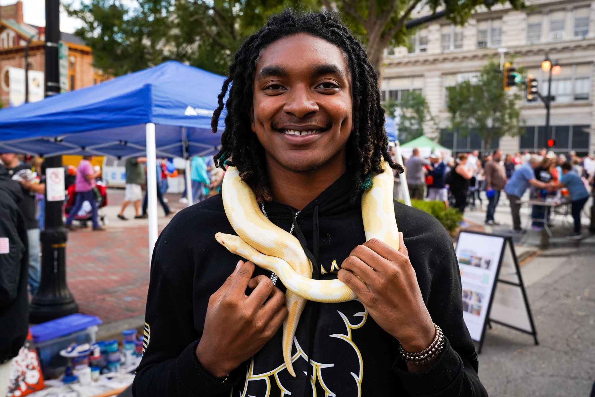 a man with dreadlocks is holding a snake around his neck