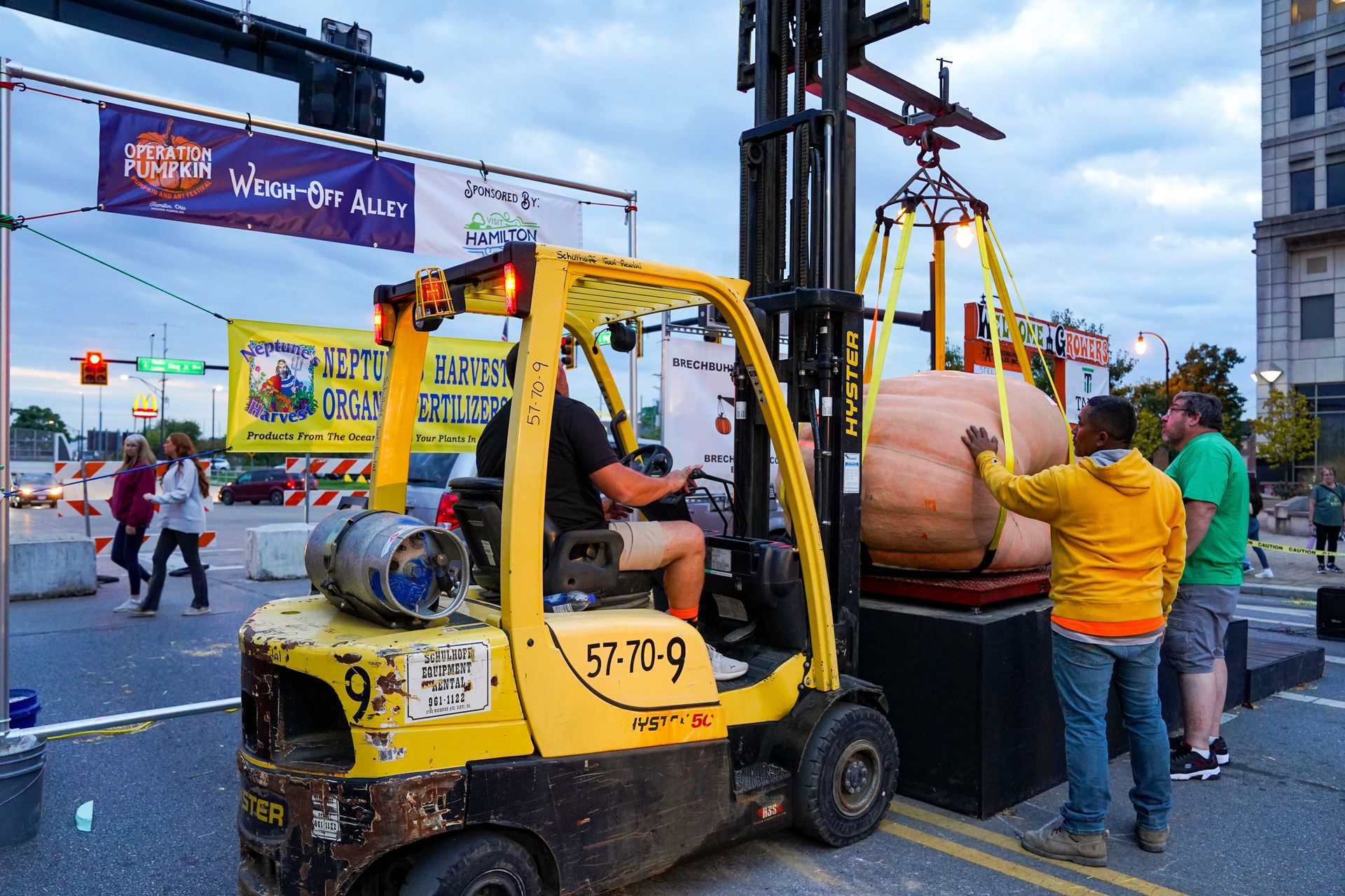 a man is driving a yellow forklift carrying a large pumpkin