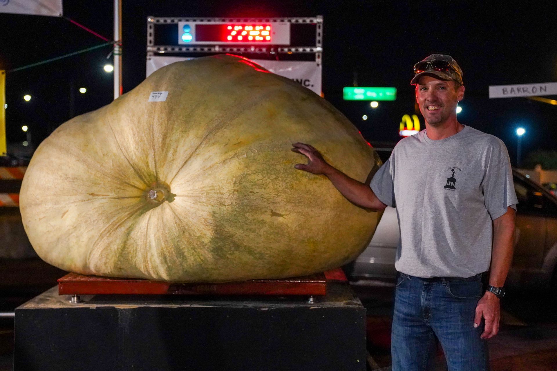 a man is standing next to a very large pumpkin