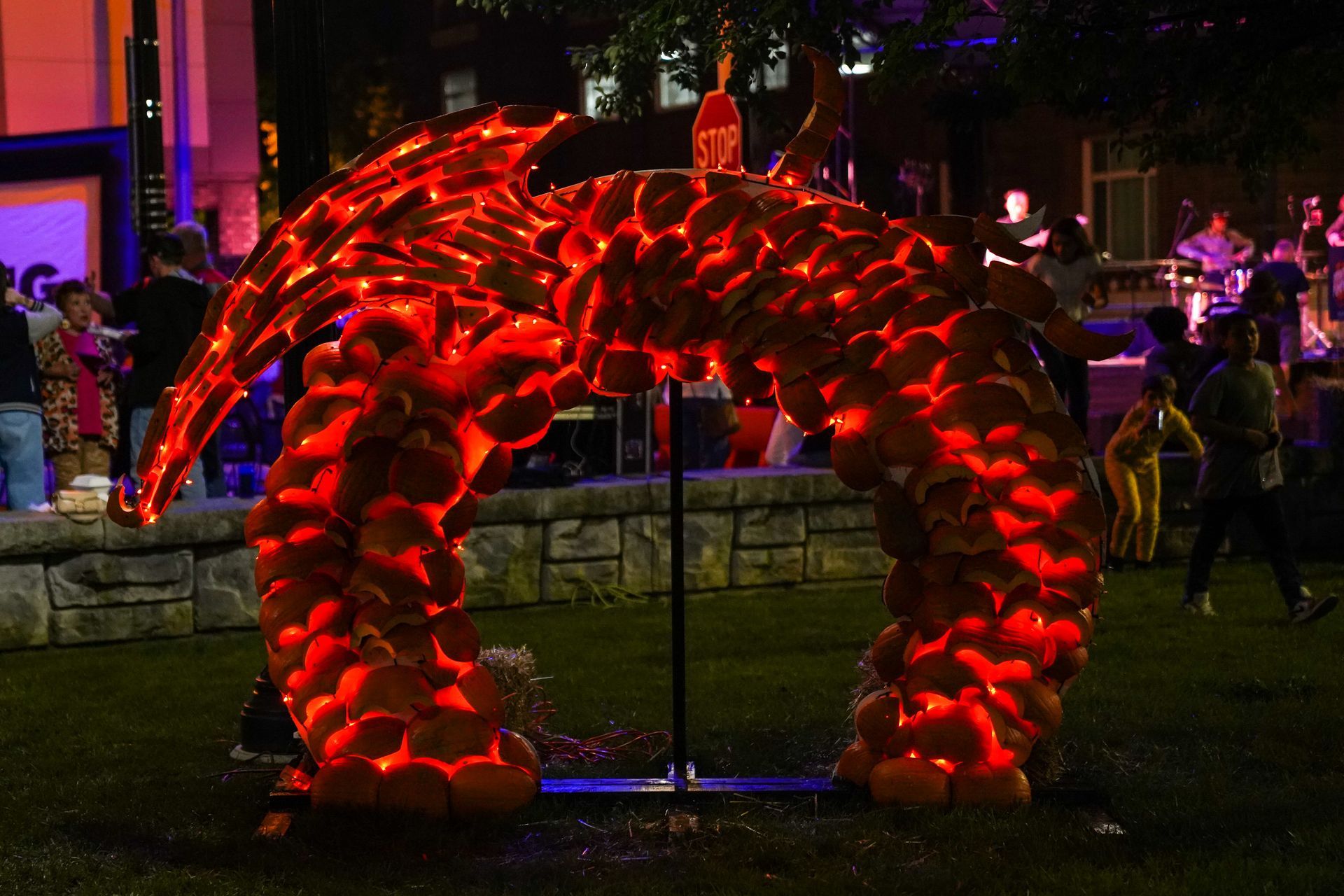 a sculpture of a dragon made out of pumpkins is lit up at night