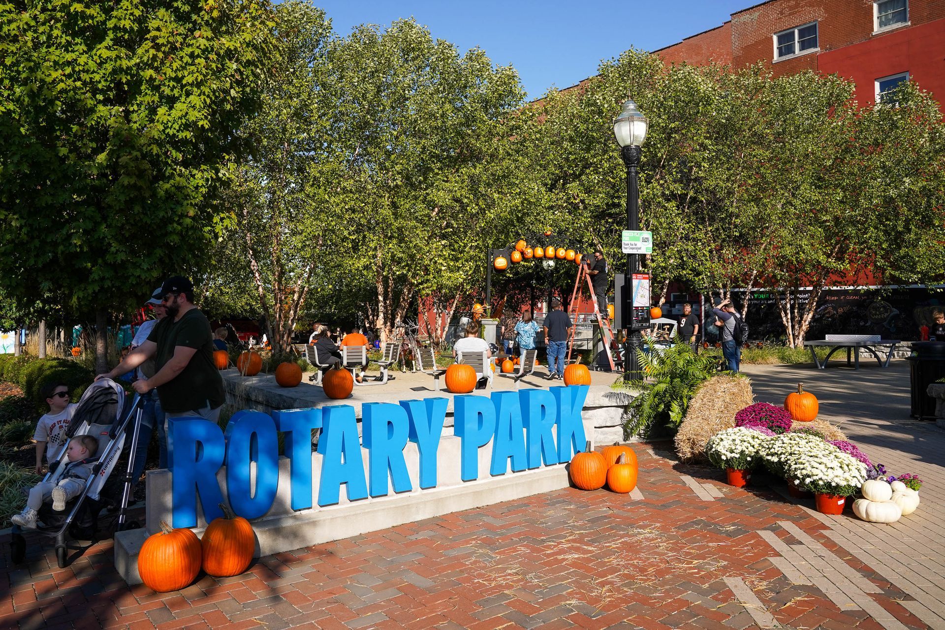 a man pushing a stroller in front of a sign that says rotary park