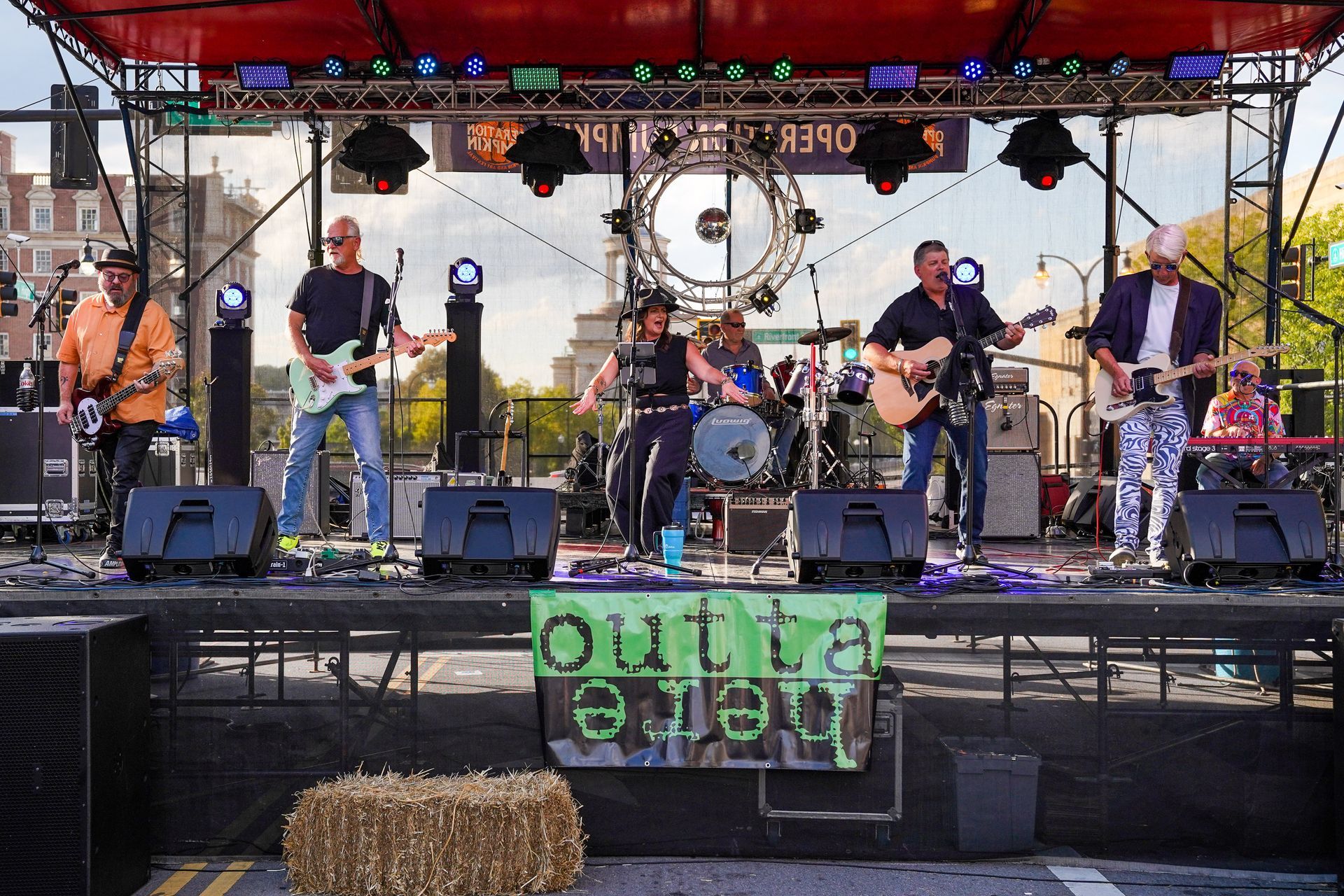 a band is playing on a stage with a sign that says outta here