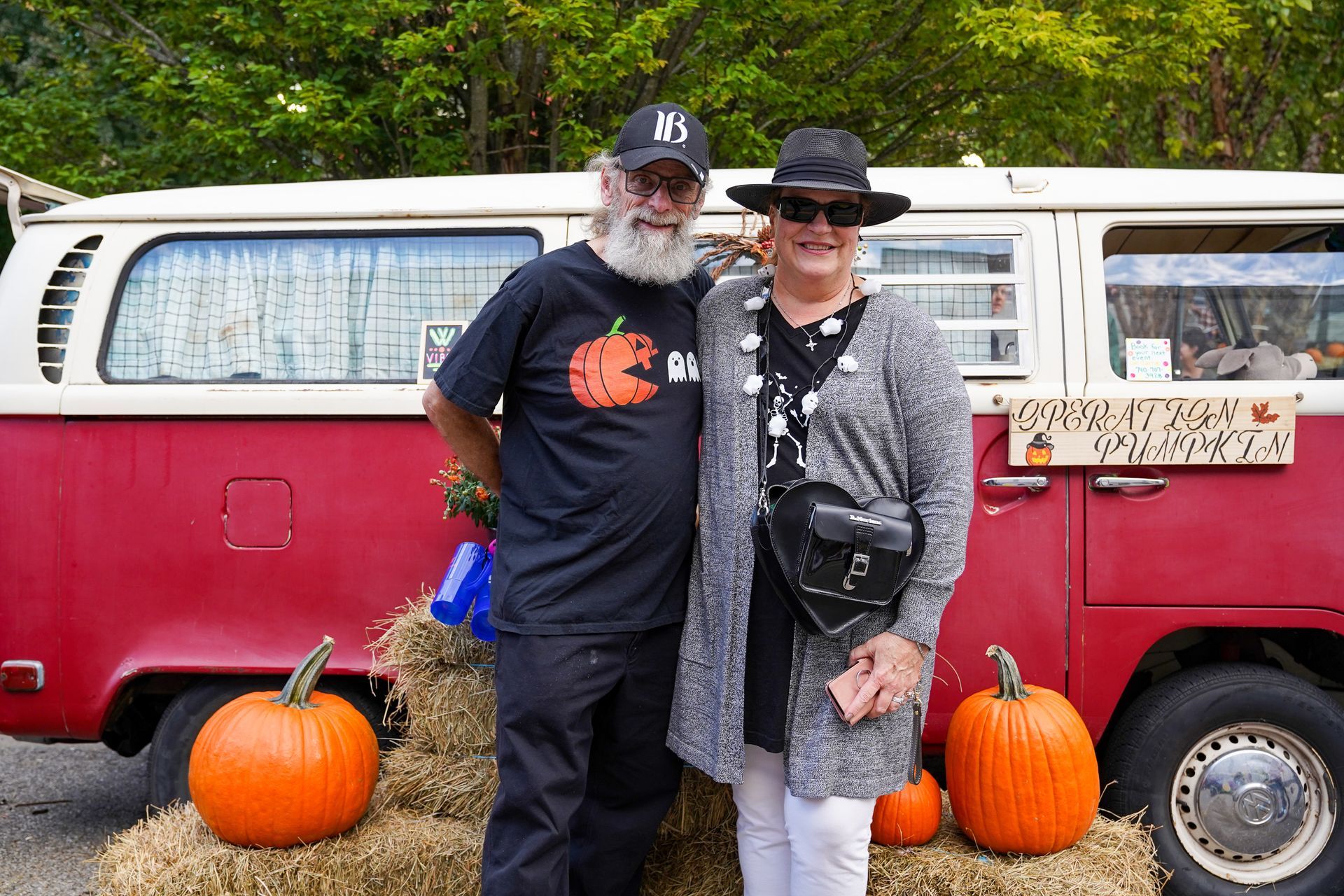 a man and a woman are posing for a picture in front of a red van