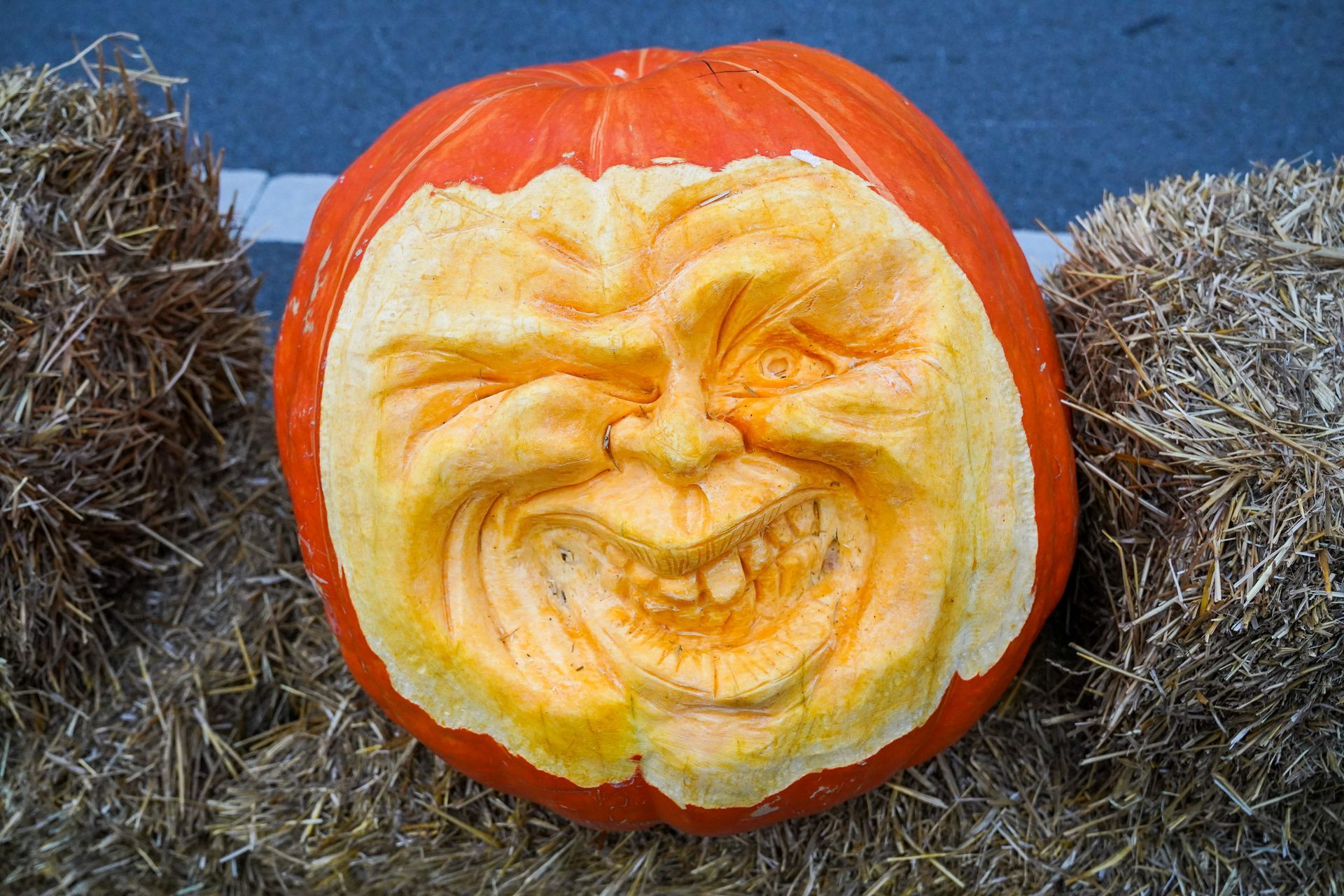 a pumpkin with a face carved into it is sitting on a pile of hay
