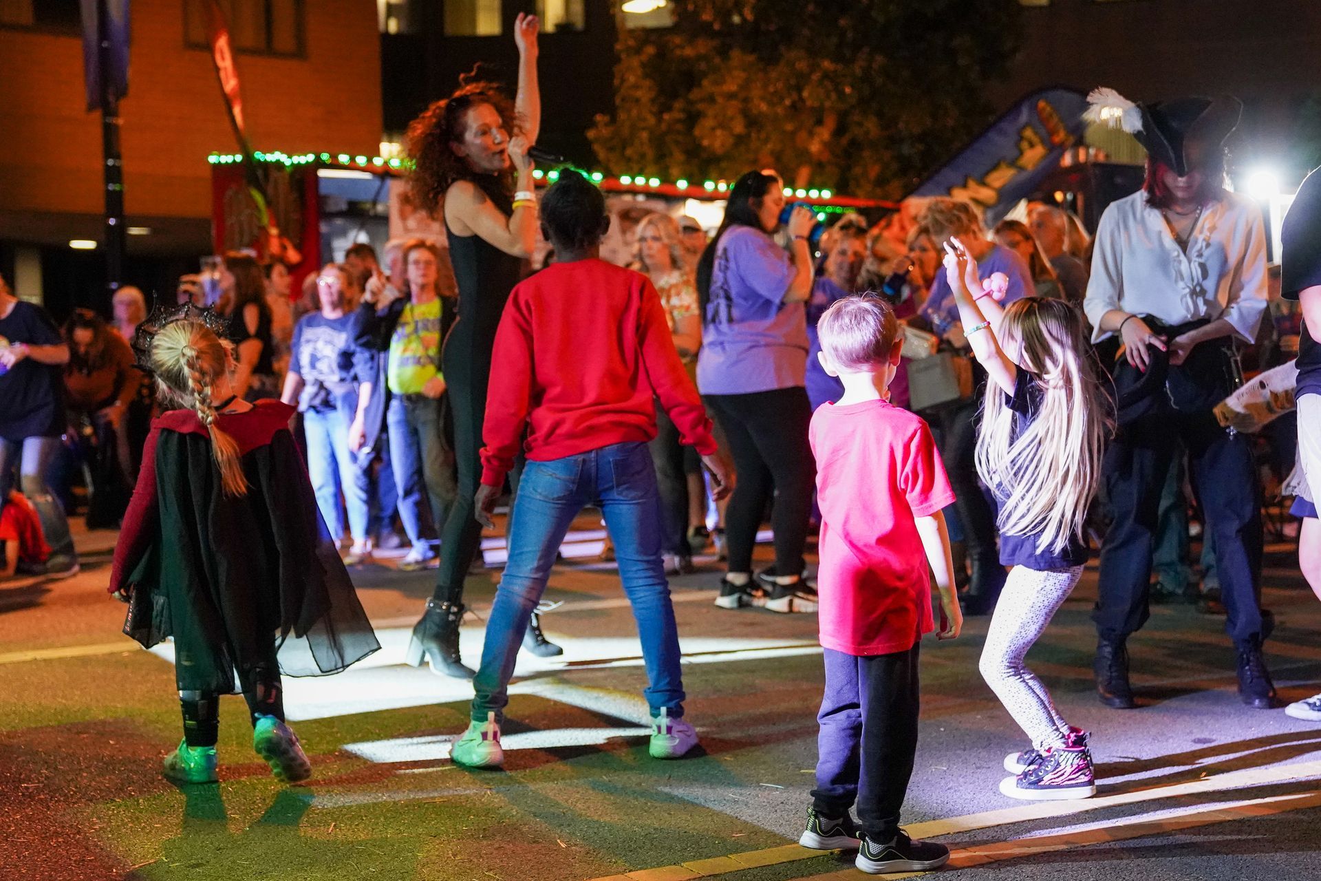 a group of people are dancing on a street at night