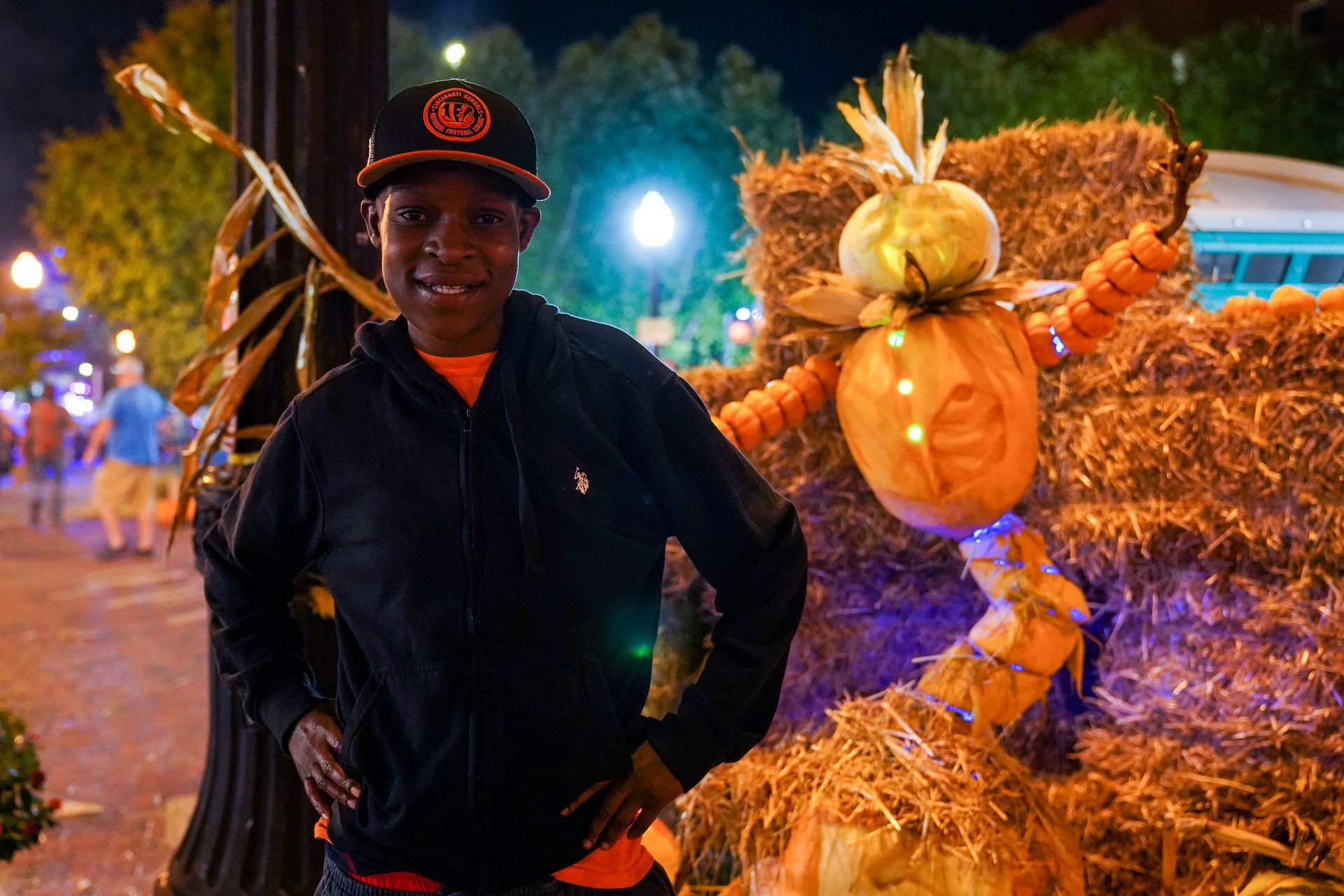 a man is standing next to a scarecrow made out of pumpkins