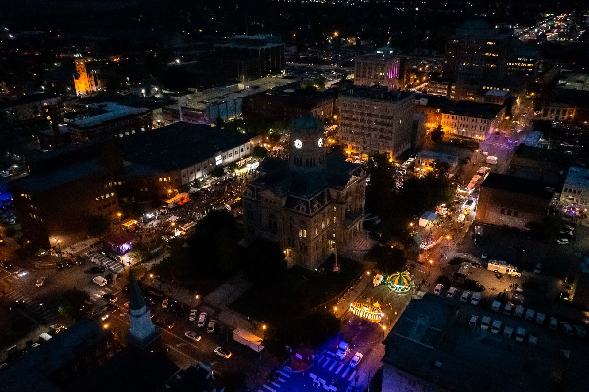 an aerial view of a city at night with a clock tower in the middle