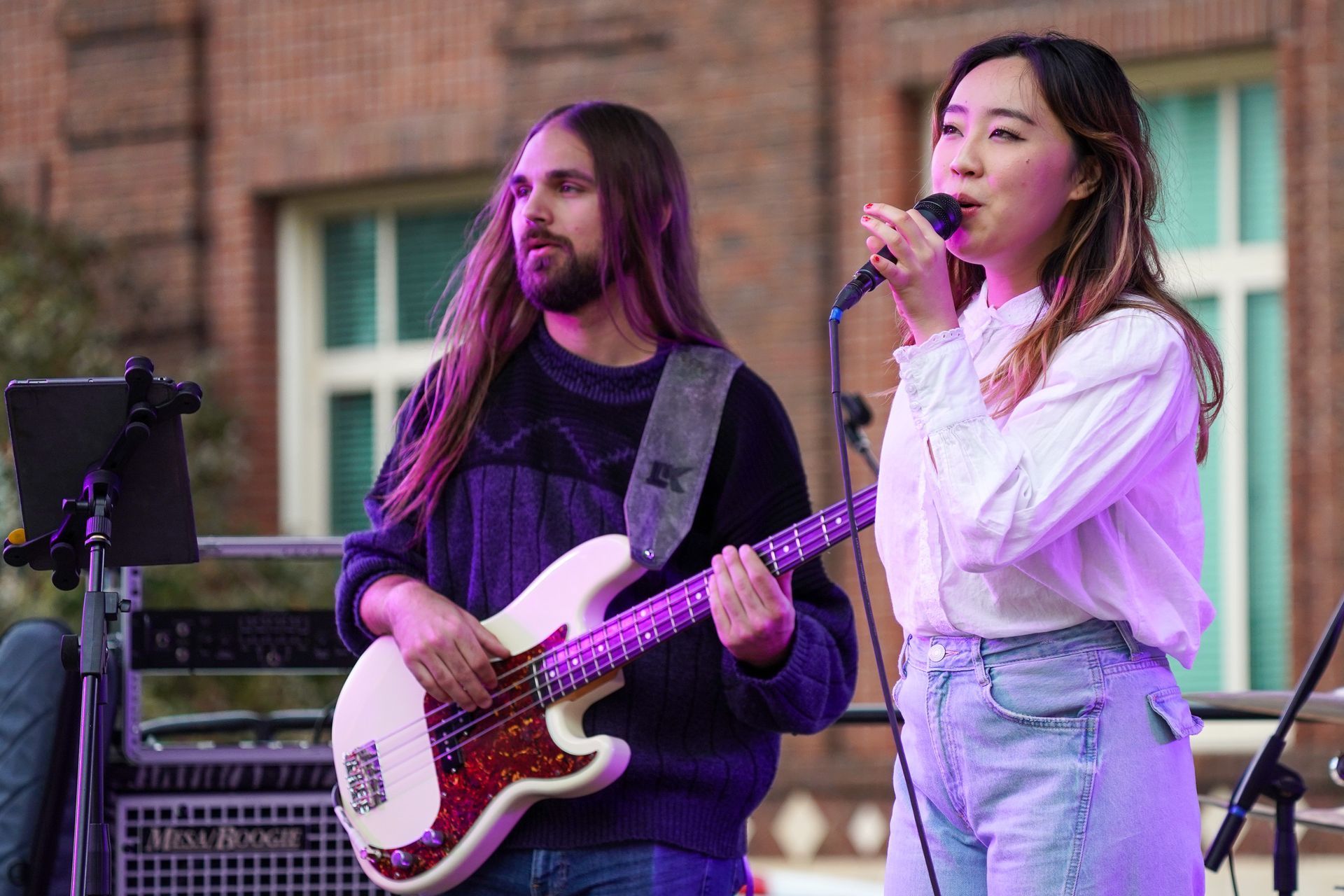 a man is playing a guitar and a woman is singing into a microphone