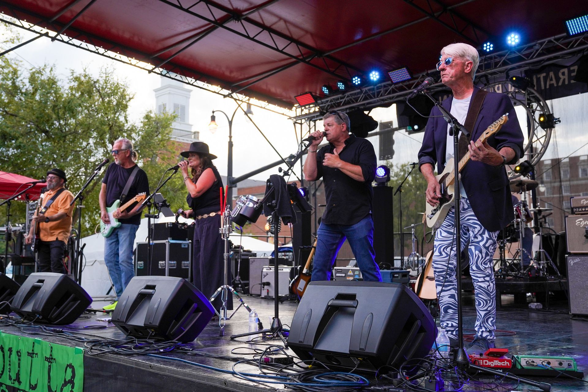 a group of people are standing on a stage playing guitars and singing into microphones
