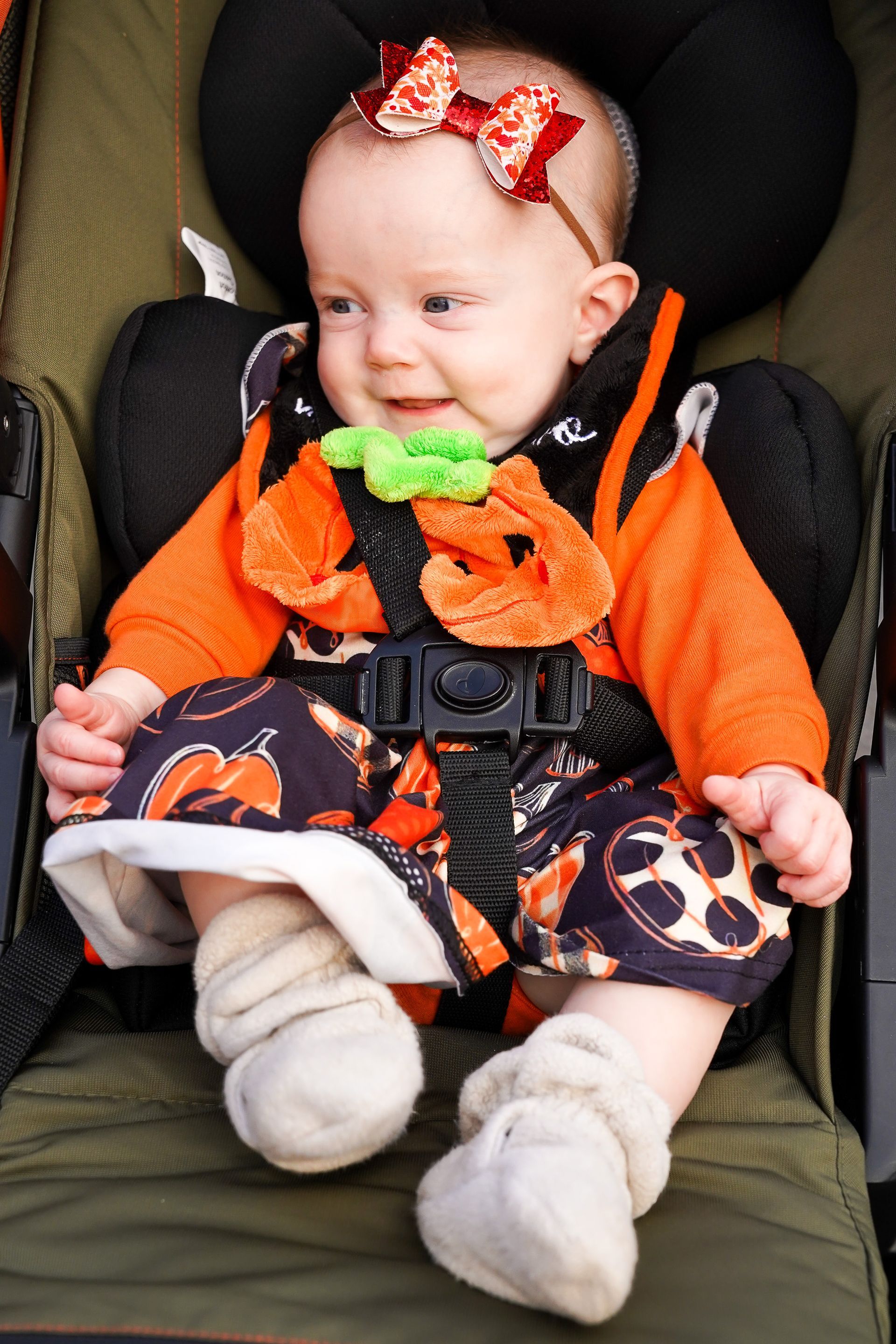 a baby wearing a pumpkin costume is sitting in a car seat