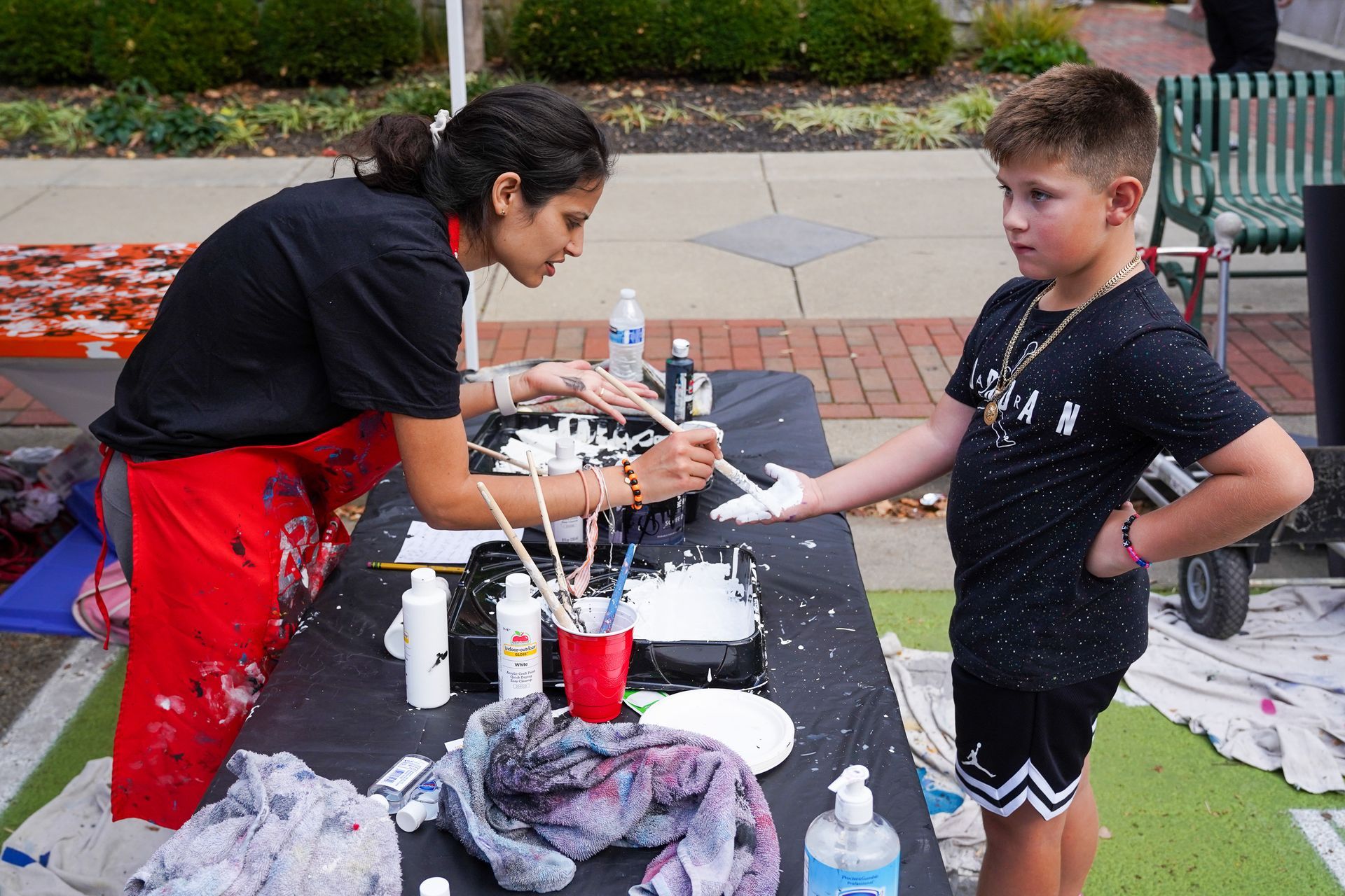 a woman is painting a boy's hands with white paint