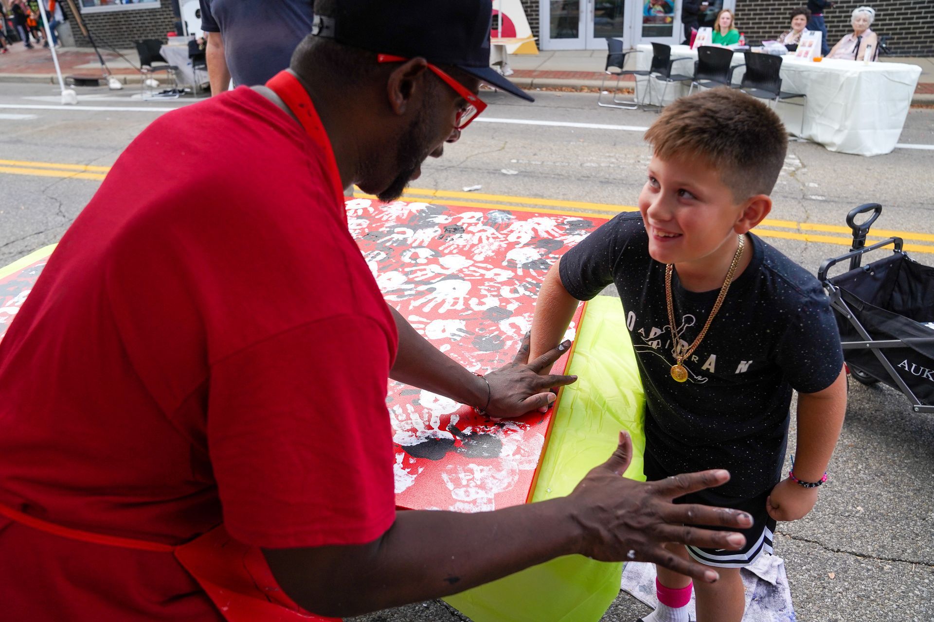 a man in a red shirt is talking to a young boy in a black shirt