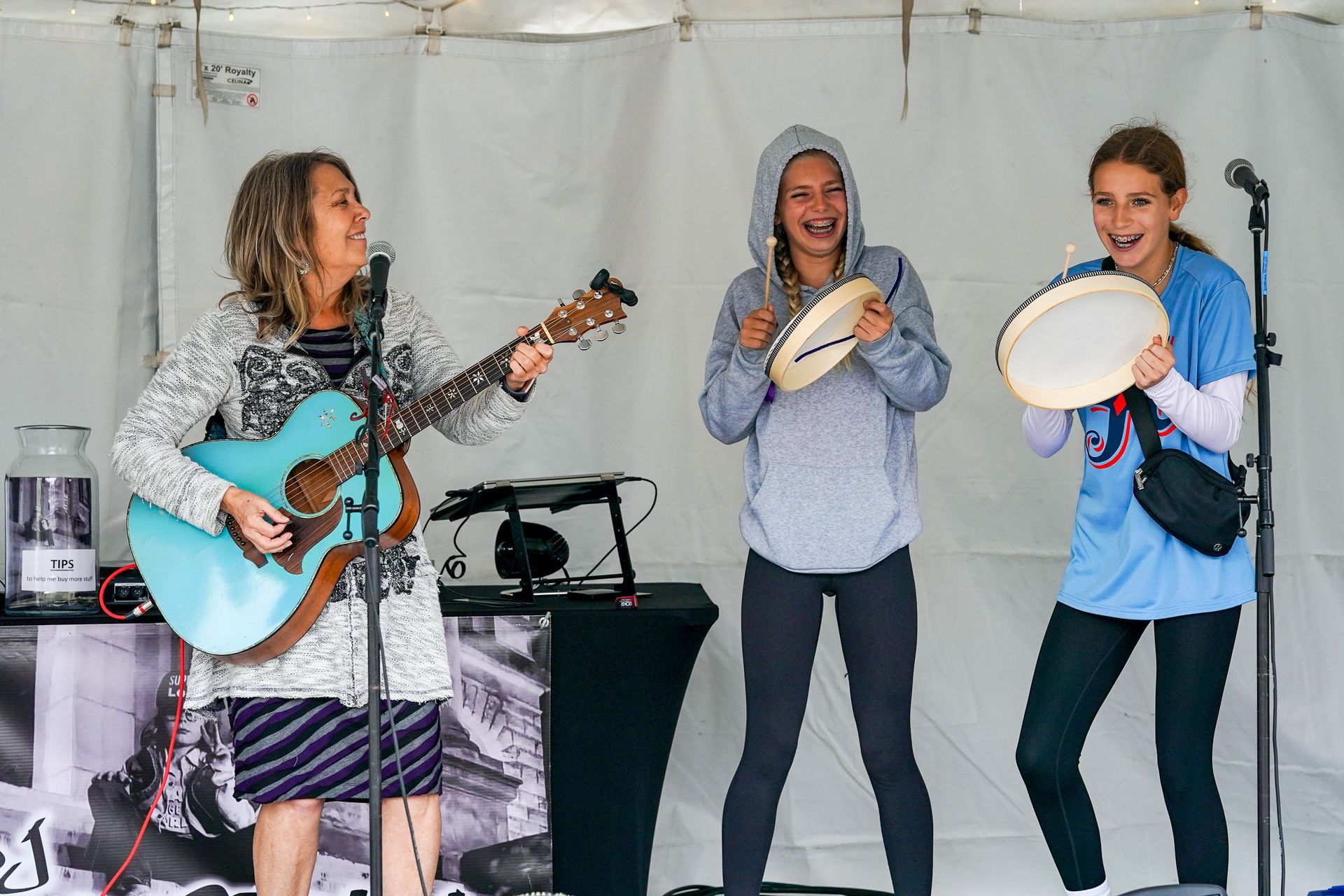 a woman is playing a guitar and two girls are playing tambourine