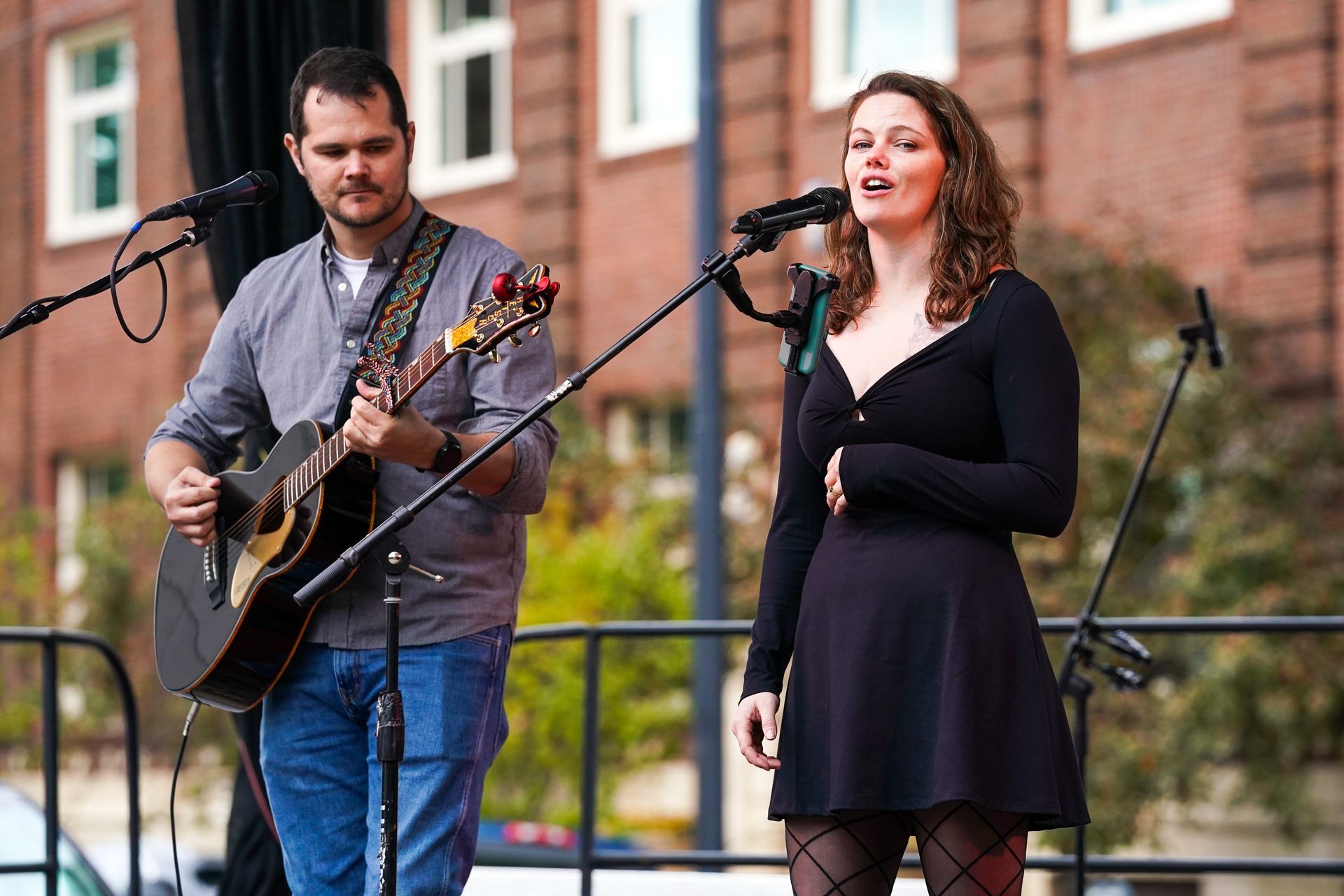 a man is playing a guitar and a woman is singing into a microphone