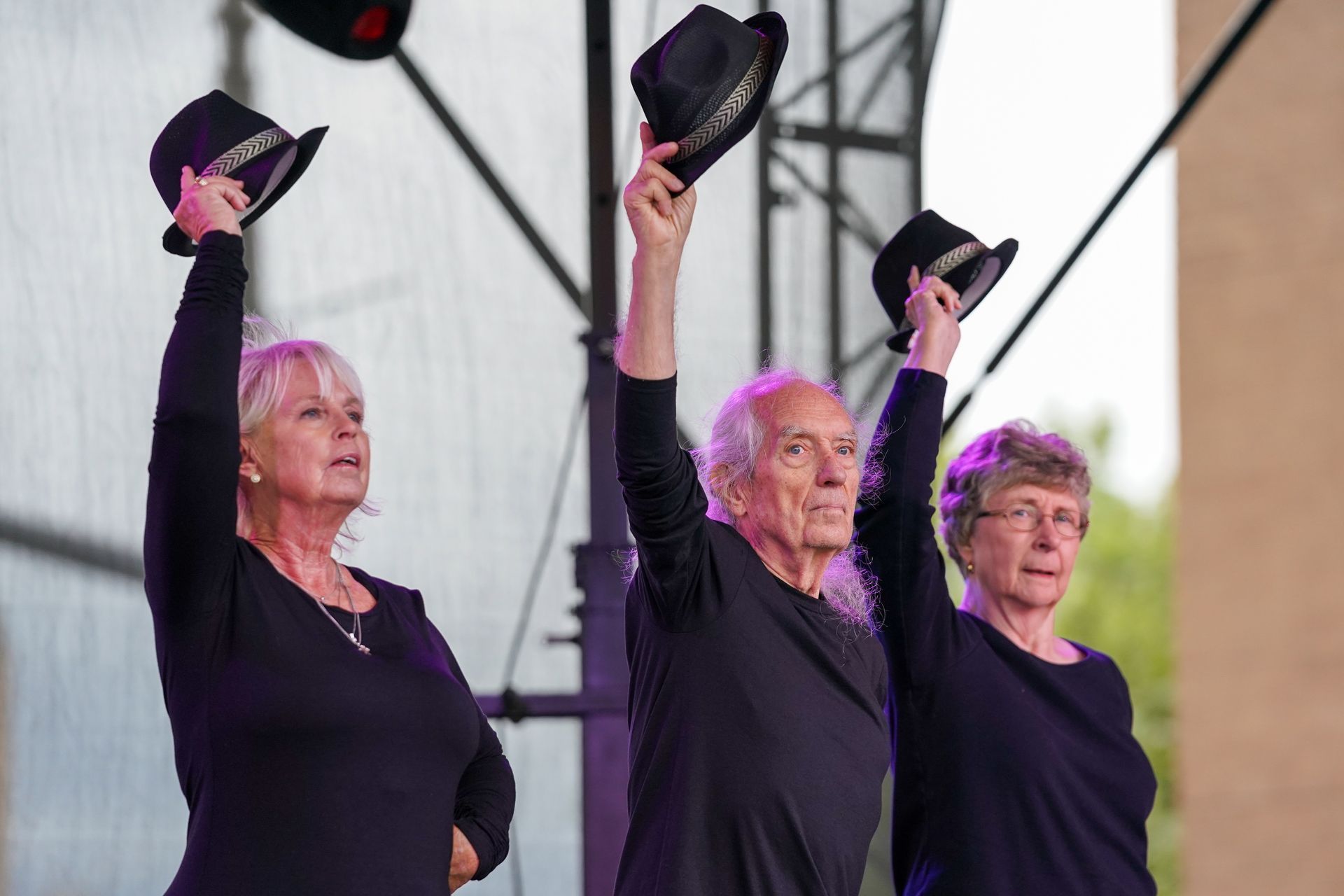three people are standing on a stage holding their hats in the air 
