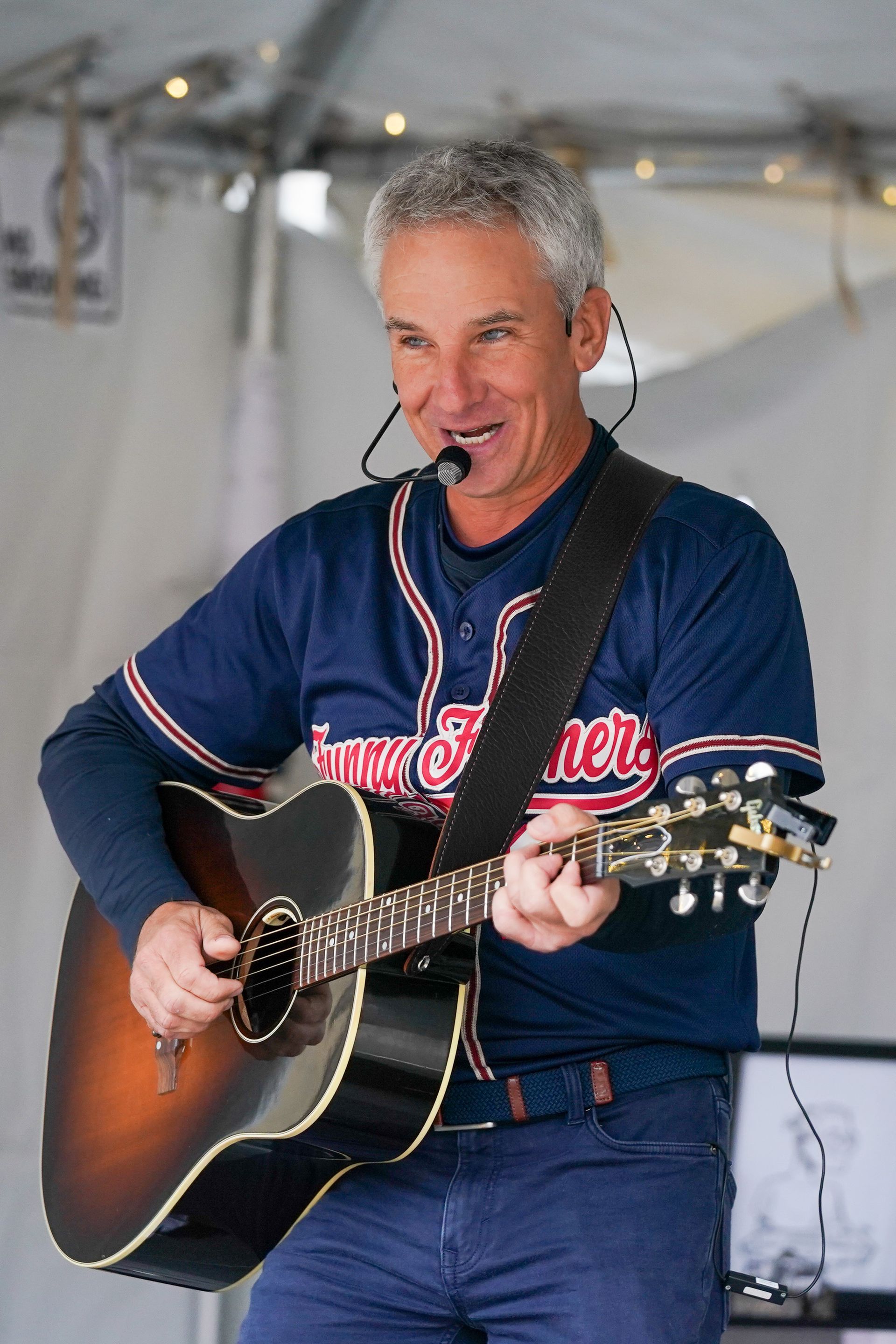 a man in a braves jersey is playing an acoustic guitar
