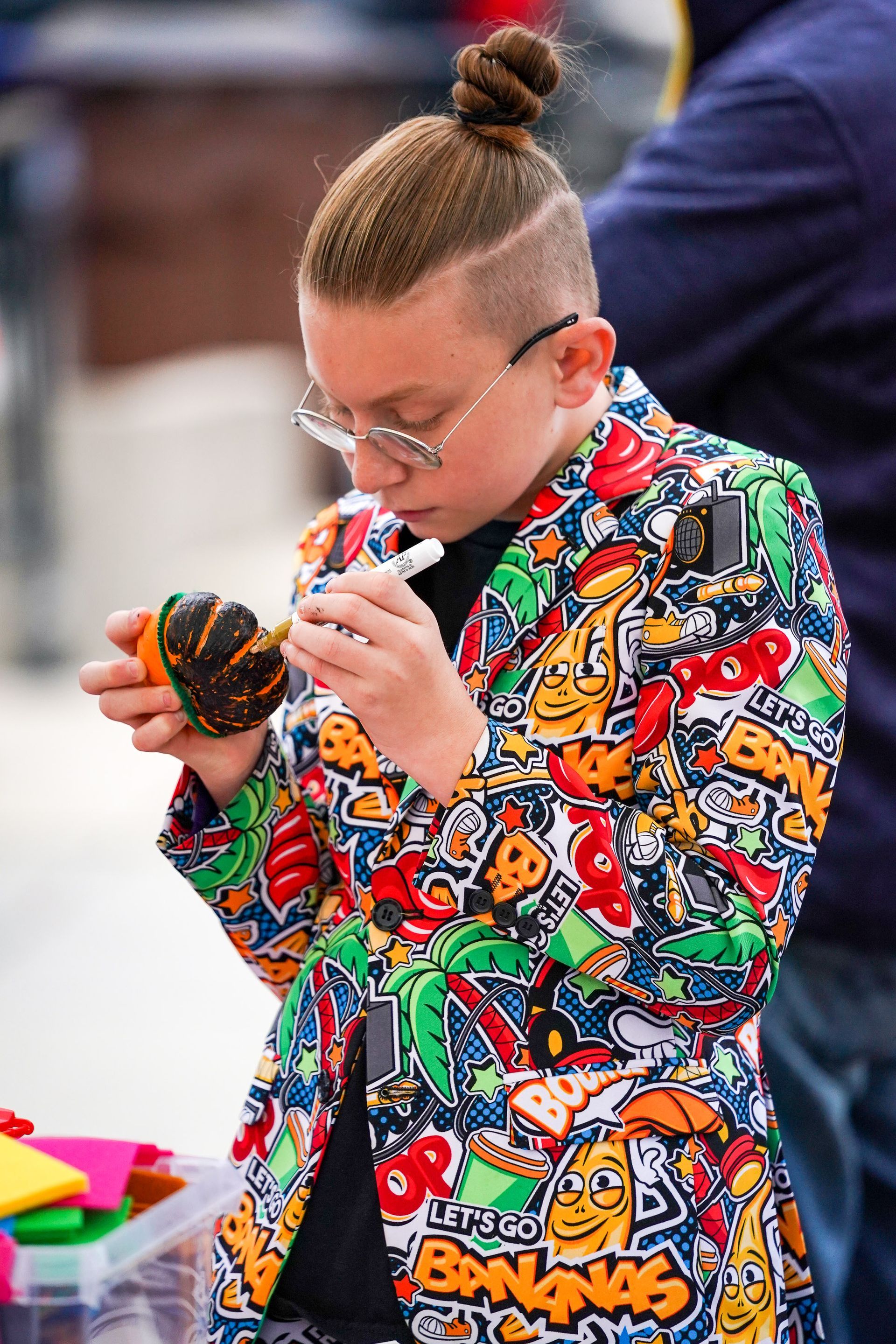a young boy in a colorful jacket is eating a donut 