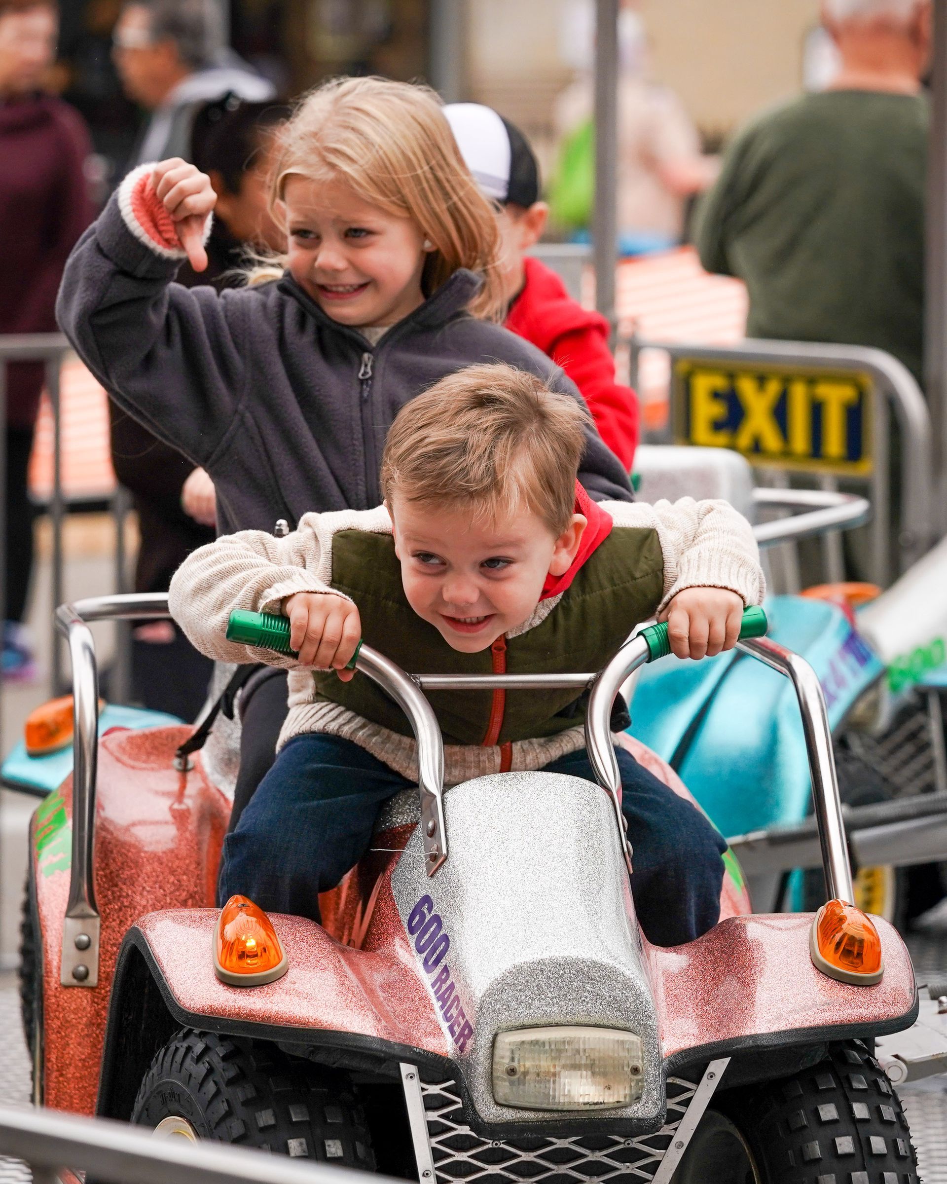 a boy and a girl are riding an atv in front of an exit sign