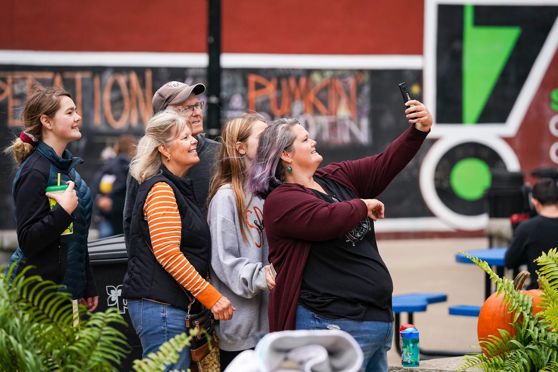 a group of people are taking a selfie in front of a pumpkin patch