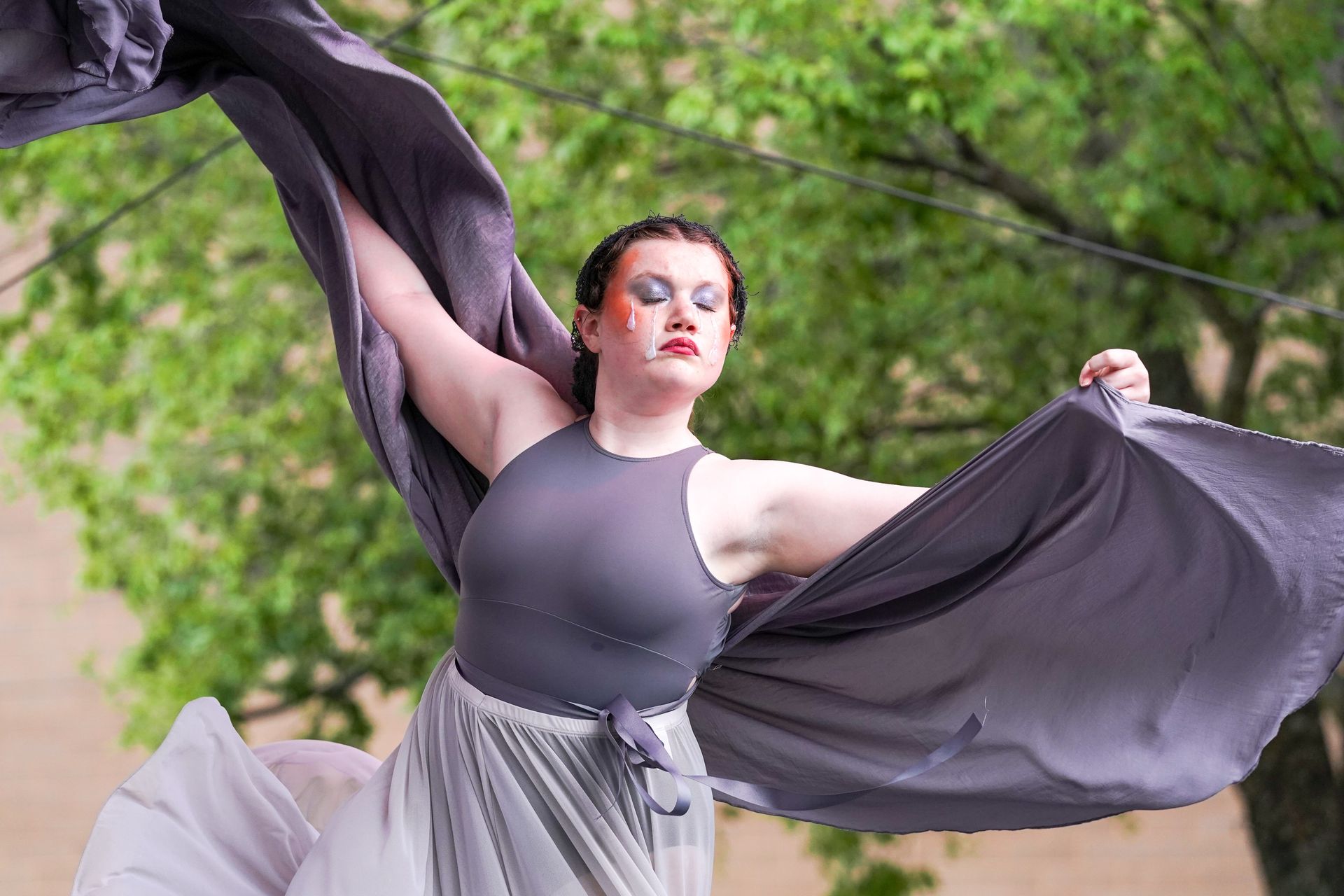 a woman in a gray dress is holding a gray cloth in her hands