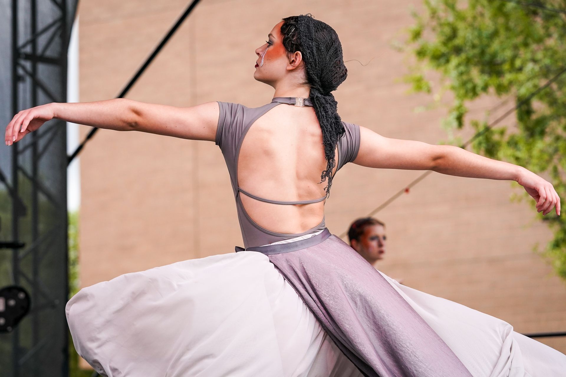 a woman in a gray dress is dancing with her arms outstretched