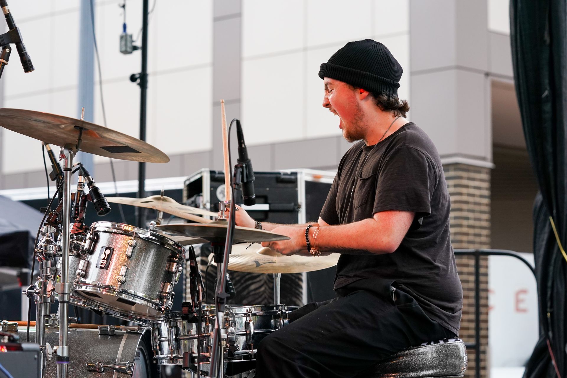 a man in a black hat is playing drums on a stage