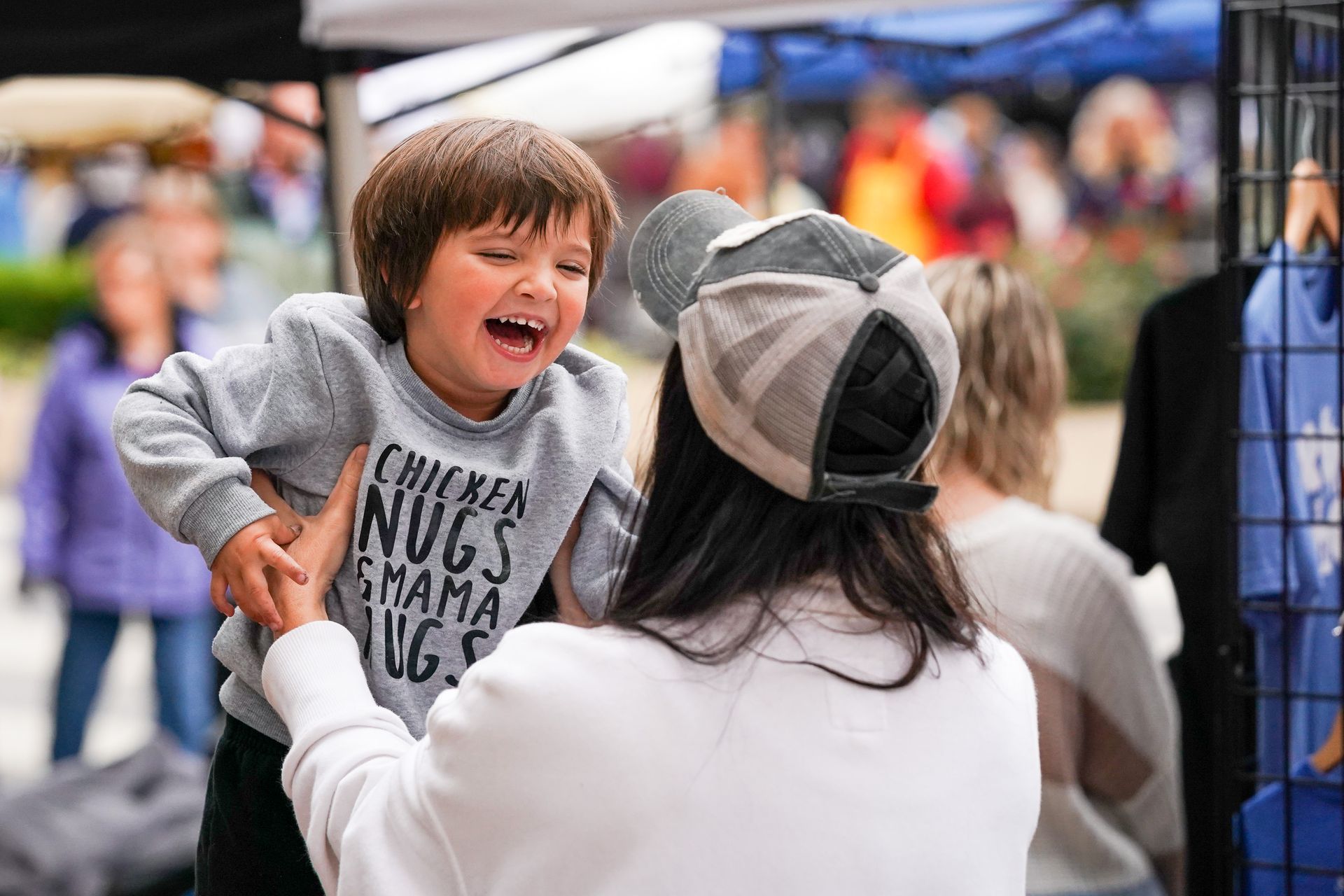 a woman is holding a little boy in her arms at a market