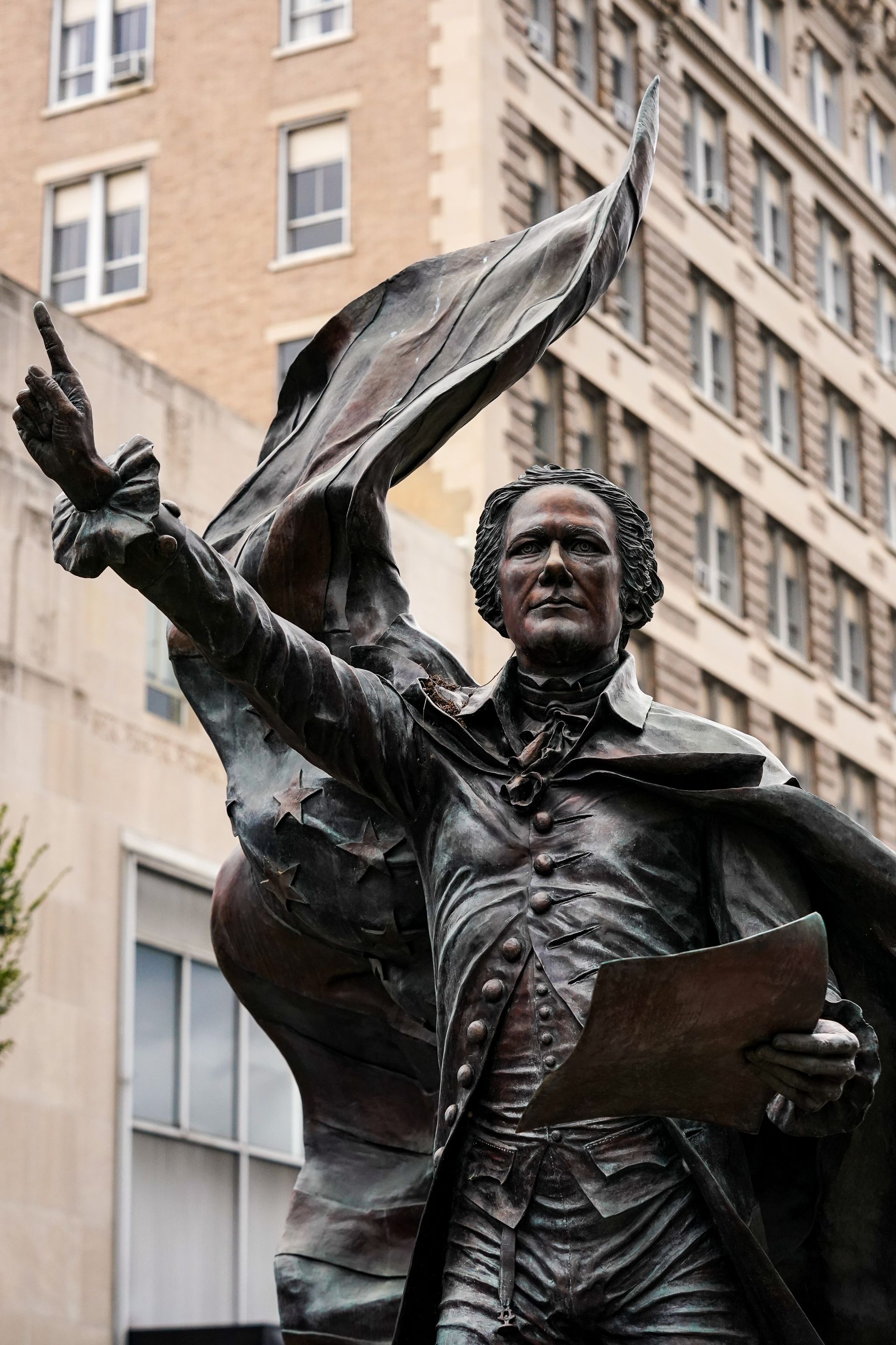 a statue of a man holding a piece of paper in front of a building